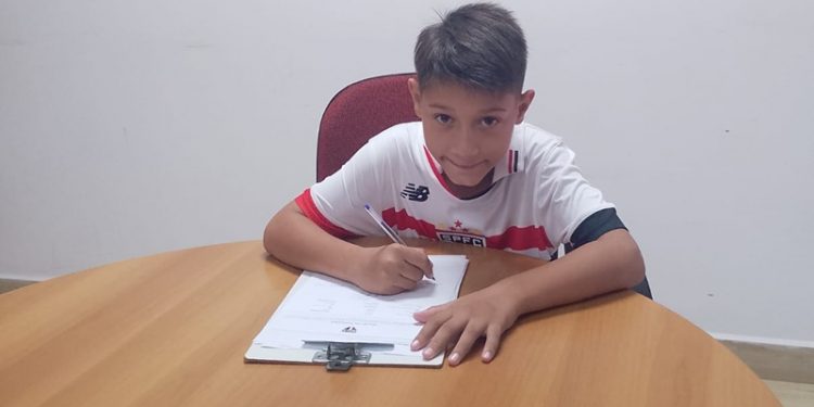 Aos 8 anos, o jovem talento Pedro Ferreira Tavares, de Avaré, está dando os primeiros passos rumo ao sonho de muitos: jogar futebol em alto nível. O garoto, que atua como meio-atacante, assinou um contrato com o São Paulo Futebol Clube para integrar as categorias de base do tricolor, marcando uma conquista precoce que enche de orgulho a cidade e sua família.  Pedro foi descoberto por Antônio Rodrigues, conhecido como Toninho, integrante da equipe técnica responsável pelas categorias sub-9 a sub-13 do clube. Antes de chamar a atenção do São Paulo, o menino treinava na escolinha do Internacional na cidade, onde demonstrou habilidade e determinação que impressionaram os olheiros.  Em agosto de 2024, Pedro passou por um teste no clube, no Centro de Treinamento de Cotia, e se destacou entre cinco selecionados, sendo convidado para uma semana de avaliação. O desempenho foi tão promissor que ele foi integrado à equipe sub-8 e, ao final do ano, aprovado para o sub-9, sendo oficialmente federado.   “Todos os meses levamos ele ao Centro de Treinamento de Cotia, onde ele fica alojado, com todas as despesas cobertas pelo São Paulo”, contou o padrasto, Nelson Pereira, destacando a estrutura oferecida pelo clube. “A avaliação do São Paulo é muito criteriosa, e a gente ficou até surpreso. A recepção no CT de Cotia é algo que deixa qualquer um sem palavras”, acrescentou, emocionado com a oportunidade dada ao enteado.  Filho de Larissa Caetano, Pedro é o orgulho da família, que acompanha de perto sua jornada. “Sabemos que a caminhada é longa, mas vamos seguindo, sempre um passo de cada vez”, afirmou Nelson, refletindo a cautela e o apoio que guiam o jovem atleta.  Em uma mensagem inspiradora enviada ao A Voz do Vale, Pedro deixou um recado para outros jovens sonhadores: “Todos têm que correr atrás dos seus sonhos. Pensamento positivo sempre”, disse o garoto, mostrando maturidade além de sua idade.  A trajetória de Pedro já é um exemplo para as crianças de Avaré que sonham com o futebol, provando que o talento local pode brilhar em grandes palcos. A família e a comunidade acompanham ansiosos os próximos capítulos dessa história, que promete ser vitoriosa.